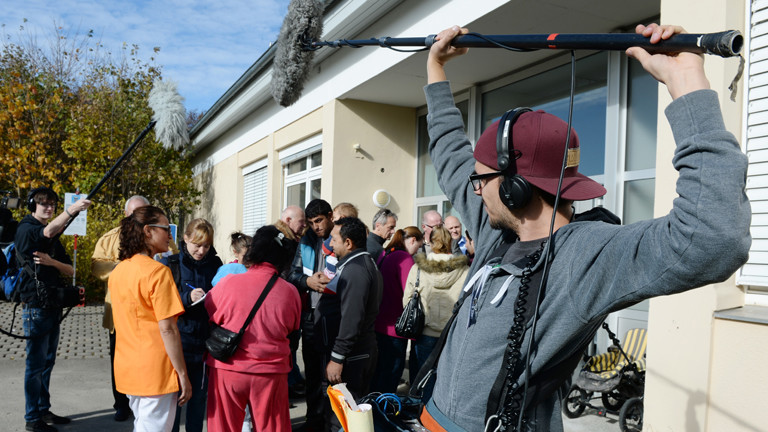 Kameraleute und Journalisten umringen eine Flüchtlingsfamilie