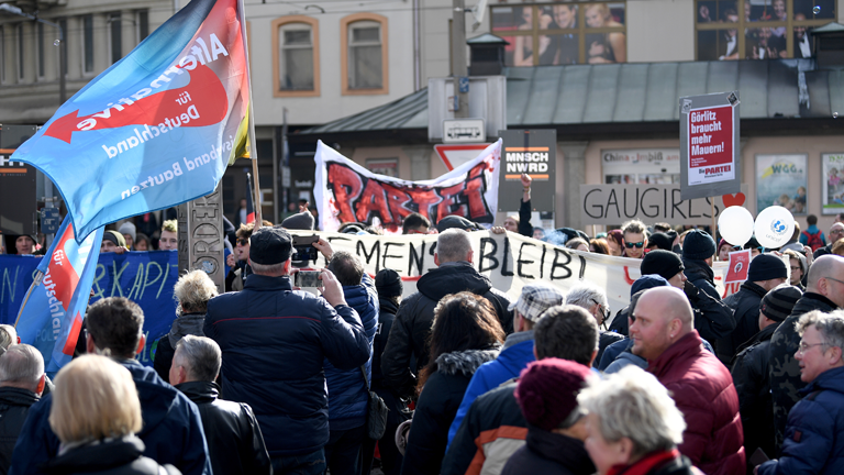 10.03.2018, Sachsen, Görlitz: Teilnehmer der Kundgebung der AfD Görlitz zur Zukunft der Arbeitsplätze in der Lausitz (vorne) und Gegendemonstranten stehen sich auf dem Marienplatz gegenüber.