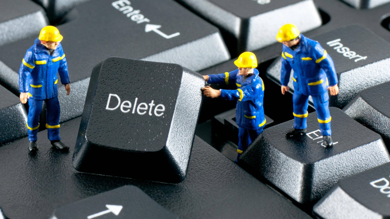 Spielzeugbauarbeiter heben eine Delete-Taste aus einer Tastatur