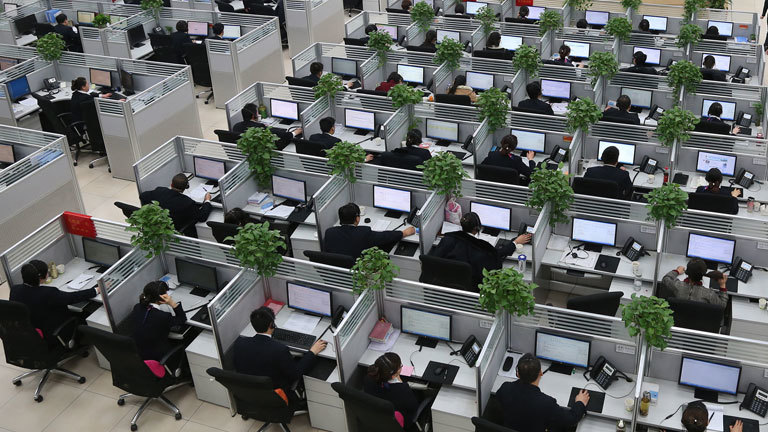 In einem Callcenter des Ministeriums der Bahn in China sitzen an vielen Schreibtischen Angestellte und arbeiten am Computer.