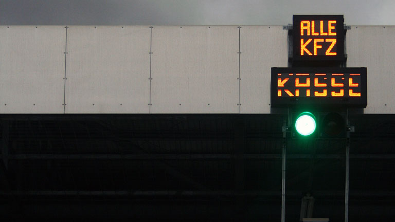Ein Schild auf dem steht: Alle KFZ - Kasse. Darunter eine grüne Lampe.
