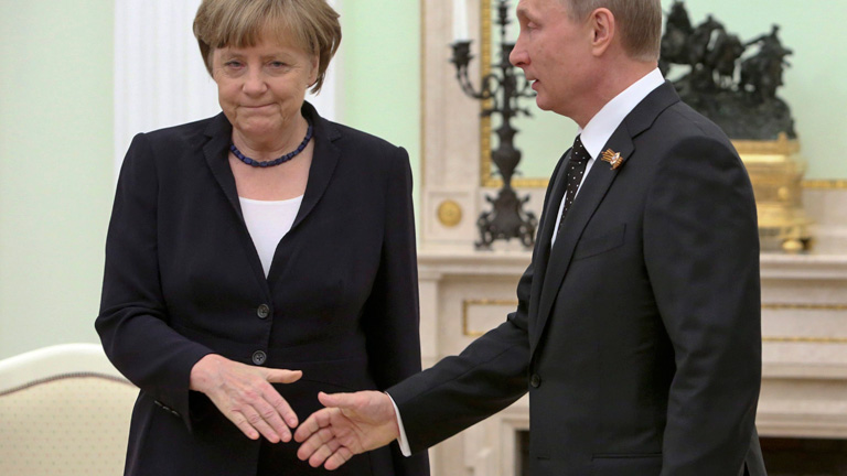 Vladimir Putin geht auf Angela Merkel zu und reicht ihr die Hand. Merkel streckt ihm ihre Hand entgegen, hat aber einen mürrischen Gesichtsausdruck, 10. Mai, bei einem Treffen in Moskau; Bild: dpa