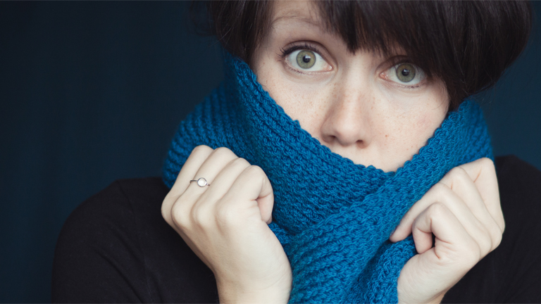 Eine Frau kuschelt sich in ihren Schal.