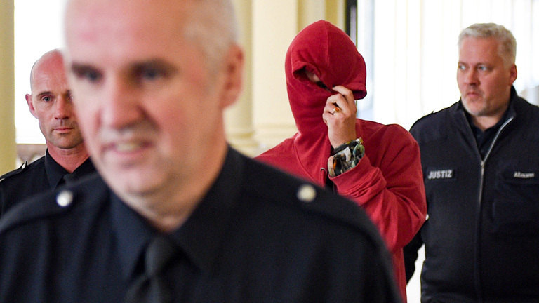 Justizbeamte führen am 28.08.2017 in Hamburg im Strafjustizgebäude einen 21-jährigen Angeklagten aus den Niederlanden zum Gerichtssaal; Foto: dpa