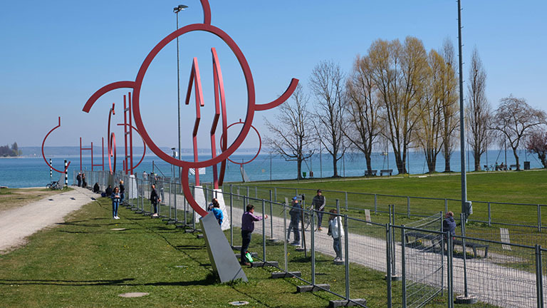 In Konstanz wurde ein doppelter Grenzzaun zur Schweiz aufgebaut; Menschen stehen auf beiden Seiten und reden miteinander (05.04.2020)