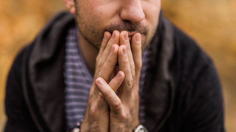 Ein Mann hält nachdenklich die Hände vor den Mund