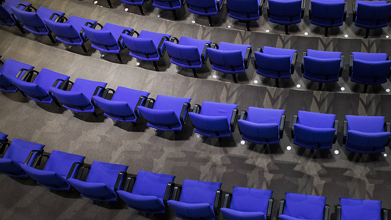 Leere Stuhlreihen im Plenarsaal des Bundestages; die Stuhlpolster sind blau.
