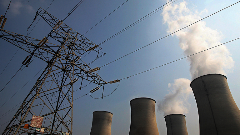 Blick auf ein Kohlekraftwerk in der chinesischen Provinz Jiangsu. Links im Bild ist ein Freileitungsmast zu sehen, rechts Schornsteine des Kraftwerks.