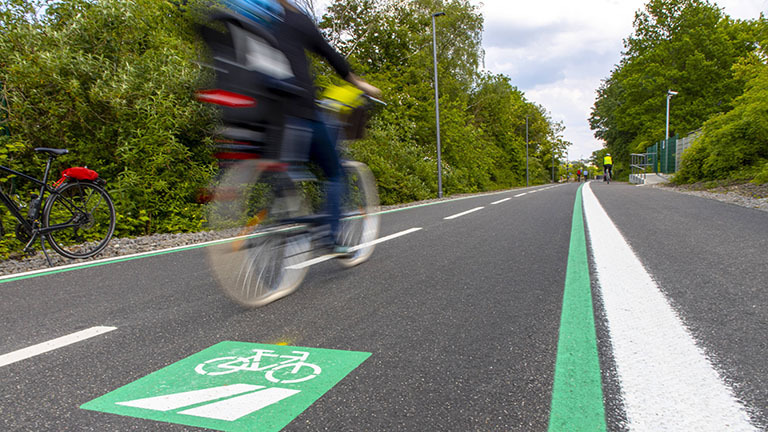 Auf dem Radschnellweg RS1, kurz für Radschnellweg Ruhr, fährt ein Fahrrad. Der Schnellweg ist eine breite Spur mit Linienführung ähnlich einer Straße.