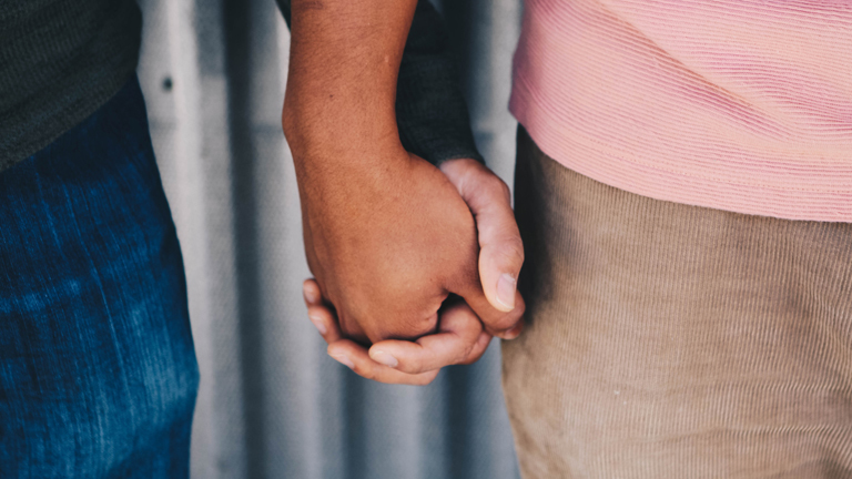 Zwei Menschen halten Händchen.