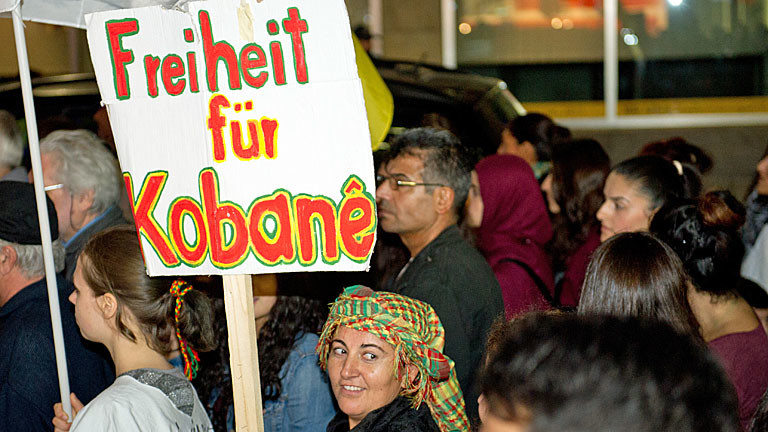 Eine Frau hält am 09.10.2014 in der Nähe des Hauptbahnhofs in Stuttgart (Baden-Württemberg) im Rahmen einer kurdischen Demonstration gegen die islamistische Terrormiliz IS und die bedrohlichen Entwicklungen in der syrisch-türkischen Grenzstadt Kobane ein Schild mit der Aufschrift "Freiheit für Kobane" in die Höhe.