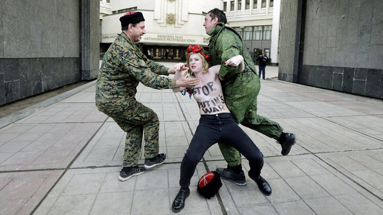 Pro-russische Aktivisten zerren am 06.03.2014 eine halbnackte Femen-Aktivisten davon, sie trägt auf ihrem Oberkörper den Schriftzug: "Stop Putins War"