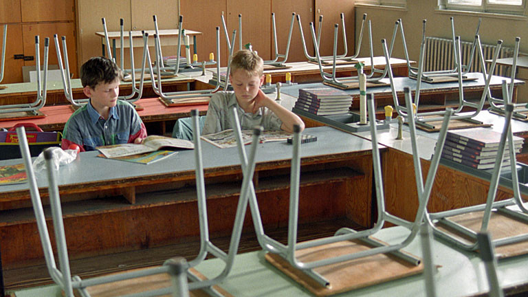 Zwei Jungs sitzen in einem Klassenraum und lesen.