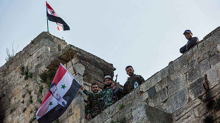Regimetreue Soldaten schwenken auf der syrischen Festung "Krak des Chevaliers" die syrische Flagge mit dem Konterfei Assads.