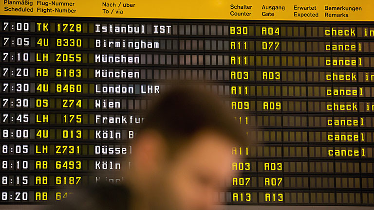 Ein Fluggast wartet auf dem Flughafen Berlin Tegel vor einer Anzeigetafel, auf der die Lufthansa-Flüge mit dem Vermerk "cancel" versehen sind.