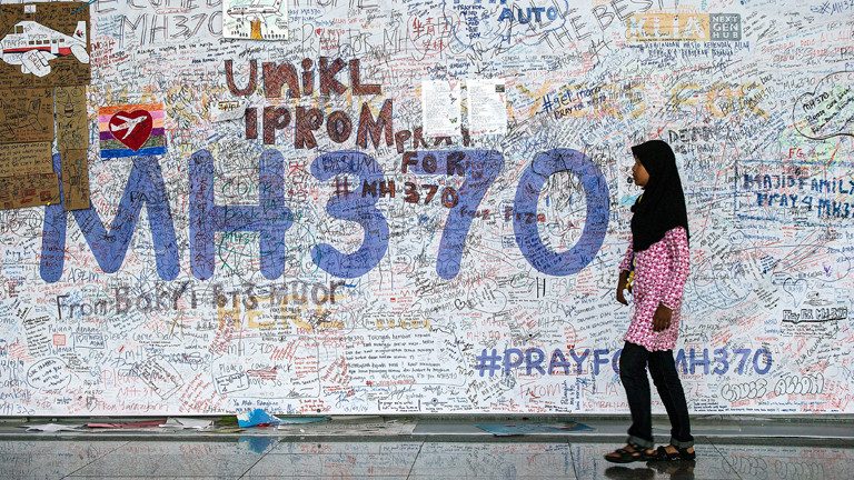 Eine junge Frau geht am 12.06.2014 auf dem Internationalen Flughafen Sepang nahe dem malysischen Kuala Lumpur an der Wand der Hoffnung für die Passagiere des vermisste Flugzeuges von MH370 vorüber