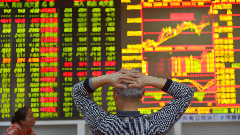 Die Börse in Hongkong: ein Broker schaut mit verschränkten Arme auf die digitale Anzeige.