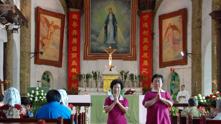 Zwei Frauen laufen am 12.08.2014 betend durch die Südkathedrale in Peking.