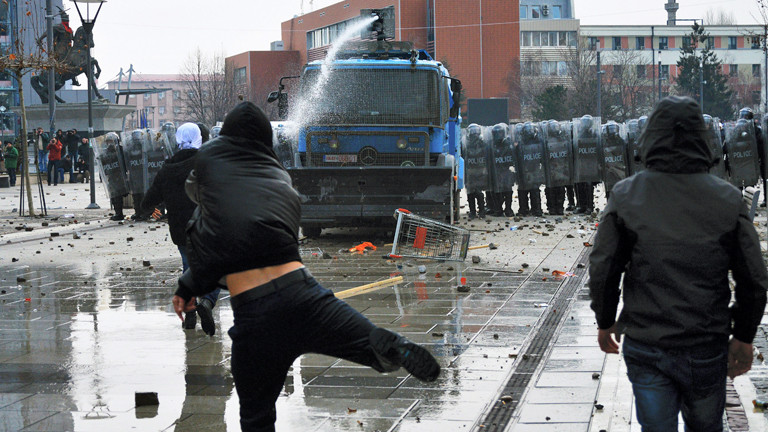 Demonstranten im Kosovo in Pristina stehen Polizisten und einem Wasserwerfer gegenüber.