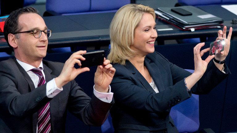 Die Bundesministerin für Familie, Frauen, Jugend und Senioren, Manuela Schwesig sitzt im Bundestag rechts neben Bundesjustizminister Heiko Maas. Beide fotografieren; Bild: dpa