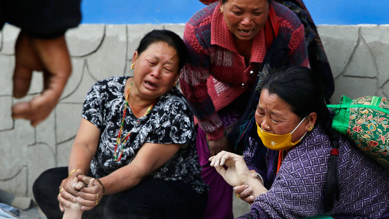 Drei Frauen halten Hände die Hände eines Toten. Sie weinen und trauern nach dem Erdbeben in Nepal; Bild: dpa