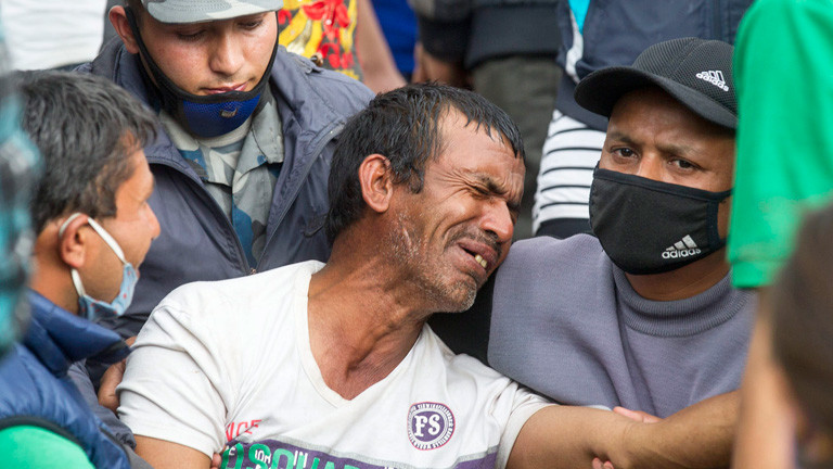 Ein Mann weint, er ist umgeben von Helfern. Nach dem Erdbeben in Nepal; Bild: dpa