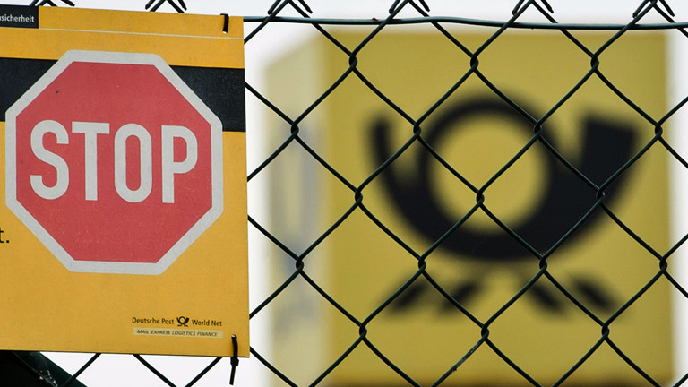 Ein STOP-Schild steht vor dem Zeichen der Deutschen Post.