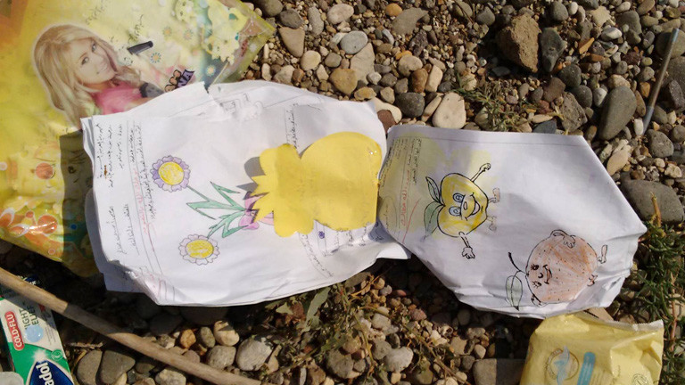 In einem Heft sind Kinderzeichnungen, das Heft liegt auf dem Boden.
