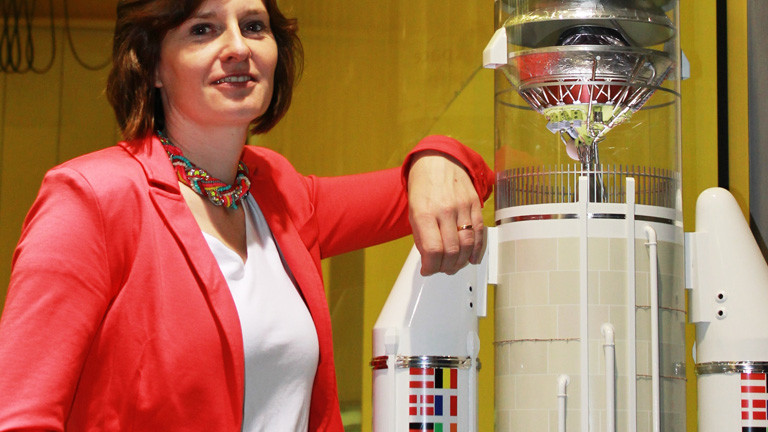 Tina Büchner da Costa lehnt sich gegen eine nachgebaute Weltraumrakete.