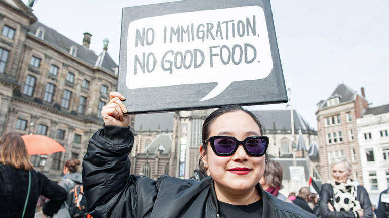Bei einer Demonstration für Frauenrechte am 11. März 2017 hält in Amsterdam eine Frau ein Schild in die Luft, darauf steht "no immigration, no good food".