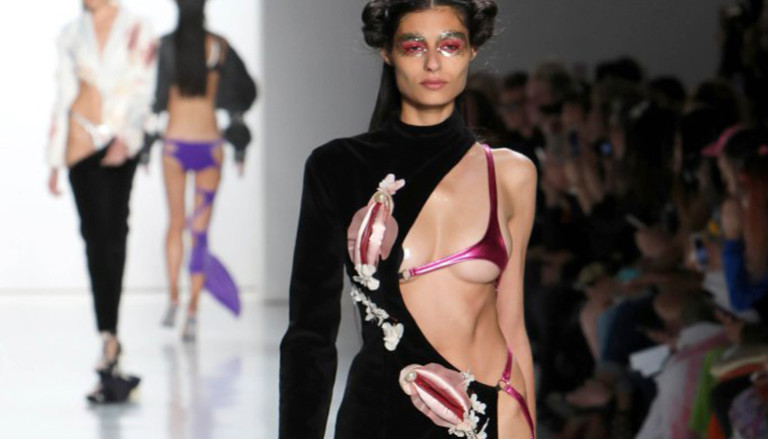 Ein Model trägt ein schwarzes Kleid mit Vulva-Applikationen.