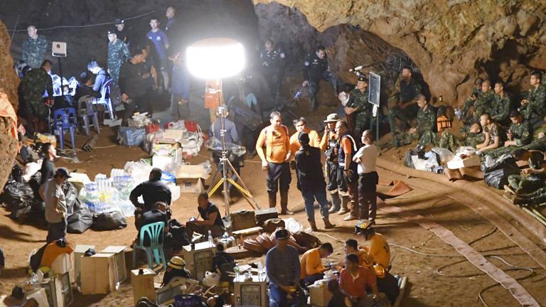 In einer Höhe sind Rettungskräfte versammelt mit ihrer Ausrüstung. Sie sollen die Jungen plus Trainer aus de Höhle retten.