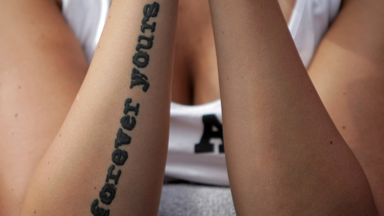 Eine Frau trägt auf ihrem Unterarm die Tätowierung "Forever young", also für immer jung; Foto: dpa