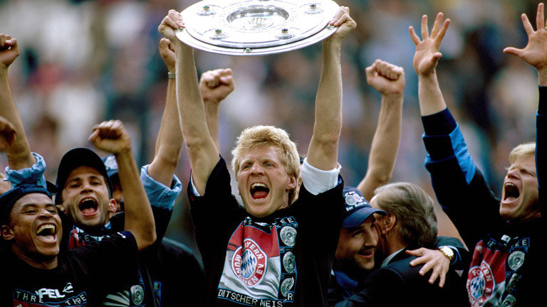 Nachdem Bayern München 2001 die Meisterschaft gewonnen hat. Steht der Fußballer Stefan Effenberg zwischen Teiler des Teams und streckt die Meisterschale in die Luft.