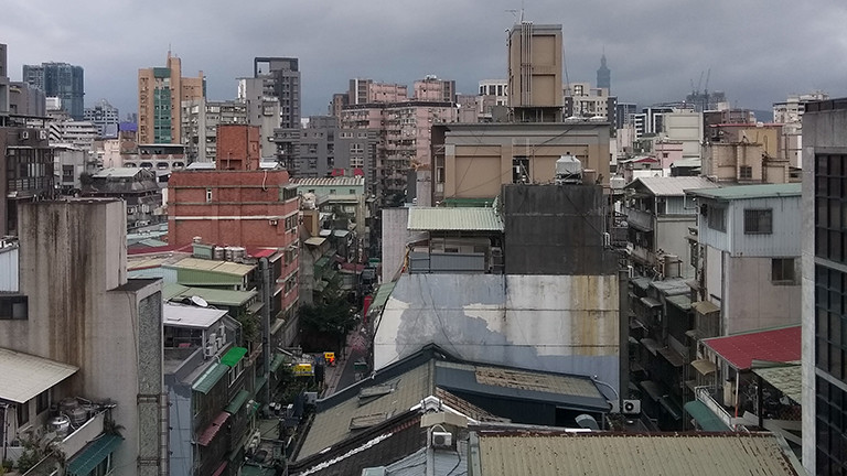 Blick aus dem Hotelzimmer auf Taipeh; viele Häuser unterschiedlicher Höhe reihen sich aneinander.