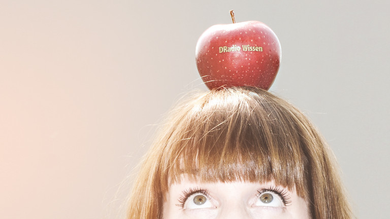 Marlis Schaum mit einem Apfel auf dem Kopf, auf dem "DRadio Wissen" steht