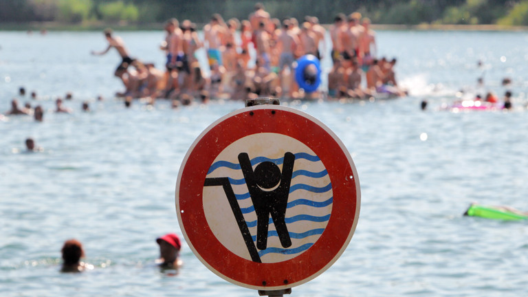 Ein Schild warnt am 04.07.2015 im Badesee in Bensheim (Hessen) Schwimmerinnen und Schwimmer vor einem stark abfallenden Ufer.