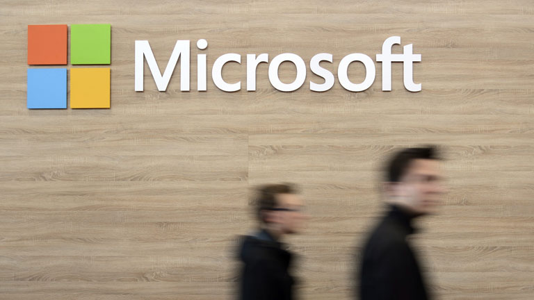 Zwei Männer gehen am Microsoft-Logo vorbei
