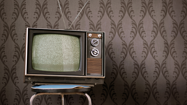 Ein alter Fernseher vor einer 70er Jahre Tapete