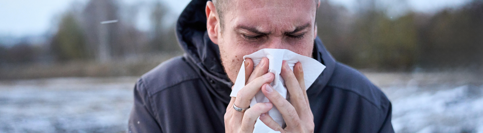 Ein Mann schnäuzt sich in ein Taschentuch.