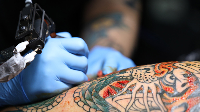 Tätowierer sticht ein Tattoo.