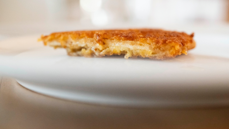 Ein veganes Schnitzel liegt auf einem Teller. Es sieht gut aus. Das Äußere ist offenbar goldfarben und knusprig, das Innere faserig und hell.