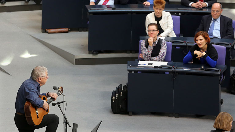 Der Liedermacher Wolf Biermann singt am 07.11.2014, während einer Gedenkveranstaltung zum 25. Jahrestag des Mauerfalls, im Deutschen Bundestag in Berlin. Im Hintergrund verfolgt die Fraktion der Linken den Gesang.