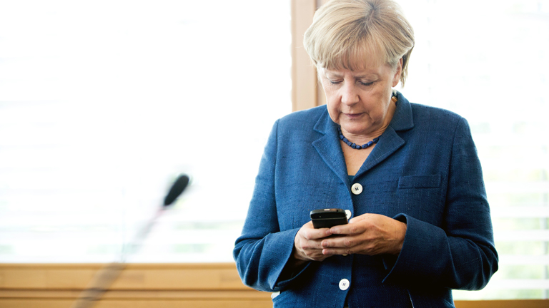 Angela Merkel schaut auf ihr Handy.