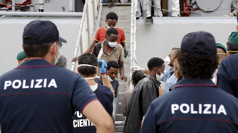 Flüchtlinge aus der Subsahara kommen am 7.9.2014 in Süditalien an. Im Vordergrund stehen Polizisten.