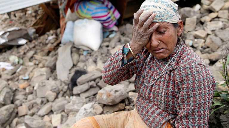 Eine ältere Frau in Nepal trauert nach der Erdbebenkatastrophe am 27.04.2015 vor ihrem zerstörten Haus.