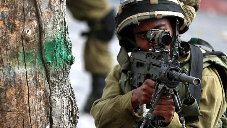 Ein siraelischer Soldat zielt am 19.10.2015 auf palästinsische Demonstranten in Hebron.