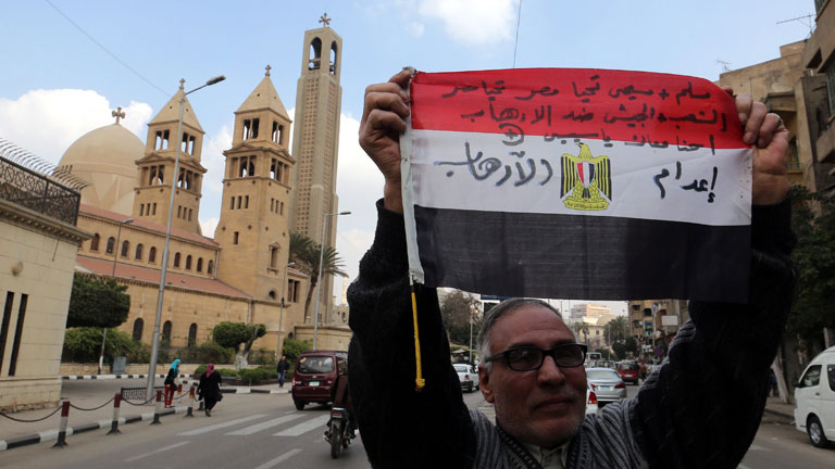 Ein Mann hält eine ägyptische Flagge in die Höhe auf der steht "exekutiere den Terrorismus". Er protestiert gegen IS, die in Libyen ägyptische Christen ermordet haben.