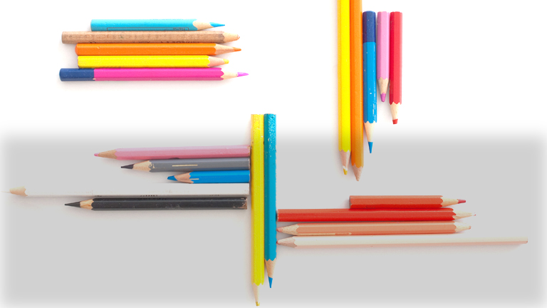Mehrere Buntstifte liegen auf einem Tisch.