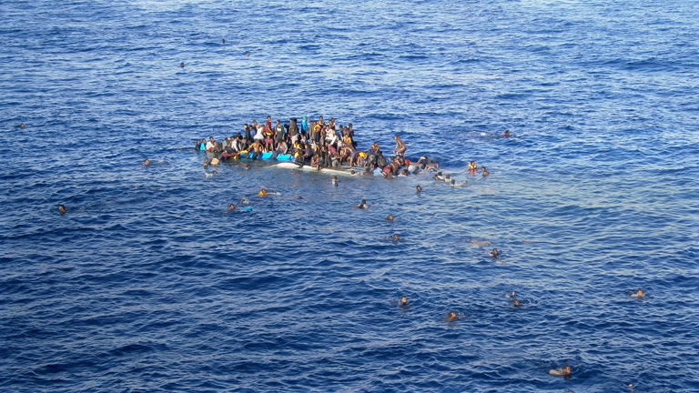 Die Aufnahme vom 12.04.2015 zeigt Flüchtlinge, die mit ihrem Boot in unmittelbarer Nähe des Frachtschiffes "OOC Jaguar" auf dem Mittelmeer gekentert sind.